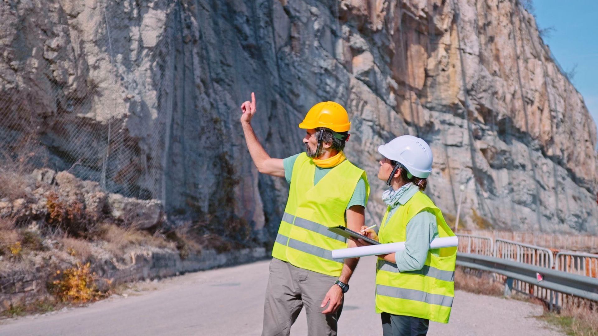 Site supervisors reviewing a rock-cut roadway alignment